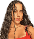 Person with long wet curly hair wearing a red top and gold hoop earrings is standing under a shaded structure with sunlight casting shadows. Description generated by AI