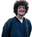 A person with curly hair is smiling and wearing a dark blue zip-up jacket over a white shirt against a white background. Description generated by AI